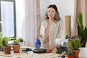 happy woman planting pot flowers at home