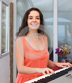 Happy woman playing piano at home