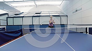 Happy woman playing the table tennis at the court