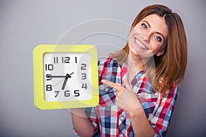 Happy woman pointing finger on clock