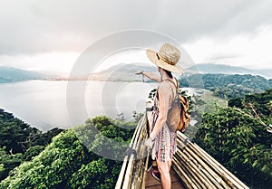 Happy woman pointing the horizon feeling free travelling the world on a inspirational background