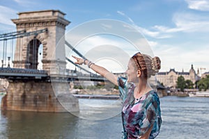 Happy woman pointing to Chain Bridge at Budapest, Hungary