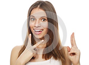 Happy woman poiting finger up at copyspace isolated on a white