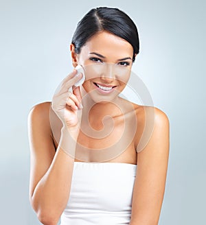 Happy woman in portrait, beauty and cotton pad for makeup removal, cleaning face or facial for skincare on grey