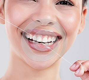 Happy woman, portrait and closeup with dental floss for teeth cleaning, hygiene or treatment on a gray studio background