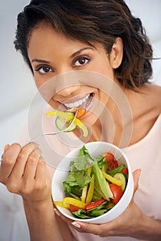 Happy woman, portrait and eating vegetable salad in bowl for diet, snack or natural nutrition in kitchen at home. Face