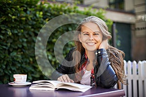 Happy woman, portrait and reading a book at cafe, outdoor and coffee shop with espresso, latte or beverage. Girl, smile