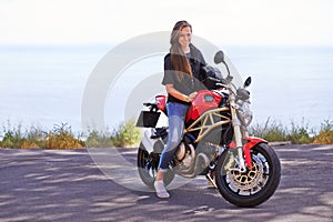 Happy woman, portrait and rider on motorcycle by the ocean coast for road trip, travel or outdoor holiday in nature