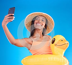 Happy woman, portrait smile and selfie on swimming vacation for profile picture with inflatable duck against a blue