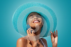 Happy woman portrait wearing blue sun hat and using mobile phone, isolated on turquoise bright background. Concept of summer beach