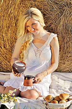 Happy woman posing with bread, milk and hay