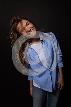 Happy woman posing with smile. Playfull curls on face. Black background