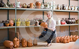 Happy woman potter carrying ceramic vessels