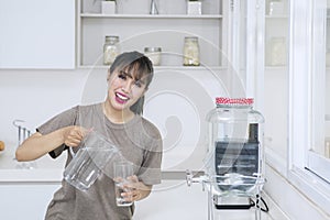 Happy woman pouring fresh water into the glass