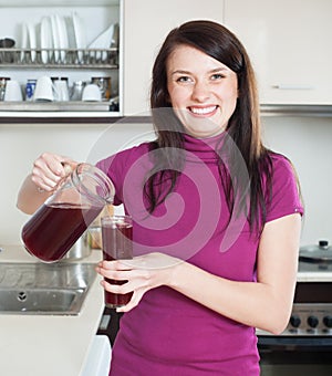 Happy woman pouring fruit-drink or juice from jug