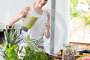 Happy woman pouring green cocktail