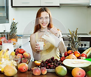 Happy woman pouring milk cocktail with fruits