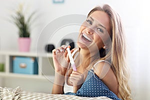 Happy woman with pregnancy test at home