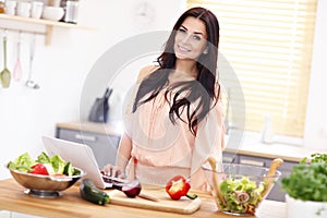 Happy woman preparing salad in modern kitchen