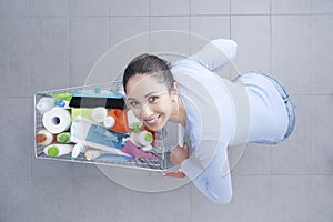 Happy woman pushing a trolley full of detergents