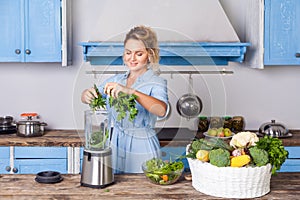 Happy woman putting ingredients into blender to make healthy smoothie for breakfast, cooking vegetables preparing salad