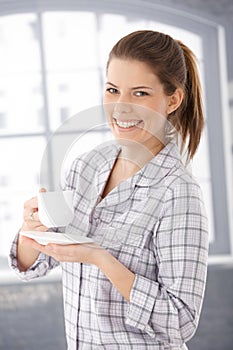 Happy woman in pyjama with coffee cup