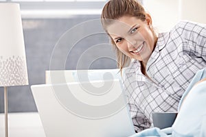 Happy woman in pyjama using laptop