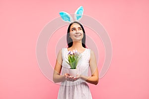 Happy woman in rabbit ears flower with painted eggs, traditional holiday, in the studio on a pink background