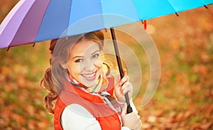 Happy woman with rainbow multicolored umbrella under rain in par