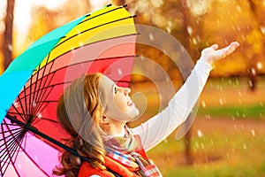 Happy woman with rainbow multicolored umbrella under rain in par