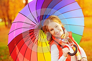 Happy woman with rainbow multicolored umbrella under rain in par