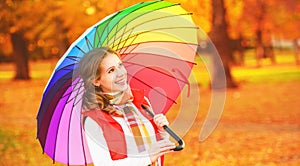 Happy woman with rainbow multicolored umbrella under rain in par