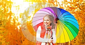 Happy woman with rainbow multicolored umbrella under rain in par