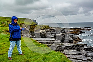 Happy woman on a rainy day at the coast with limestone rocks along the coastal walk route from Doolin to the Cliffs of Moher