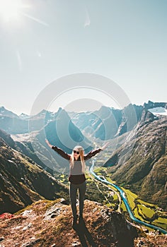 Happy woman raised hands standing on cliff mountain