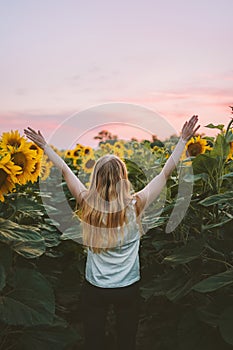 Happy woman raised hands in sunflowers field