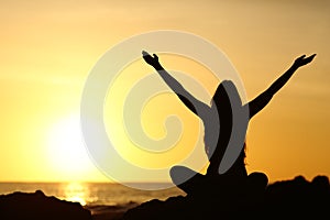 Happy woman raising arms looking at sunrise