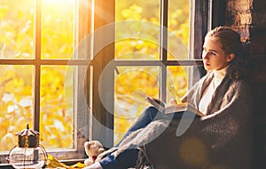 Happy woman reading book by autumn window