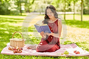 Happy woman reading book at picnic in summer park