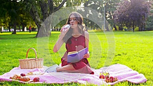 Happy woman reading book at picnic in summer park