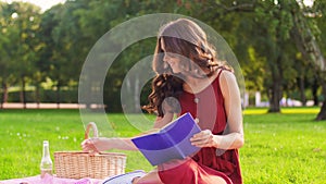 Happy woman reading book at picnic in summer park