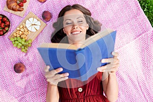 Happy woman reading book at picnic in summer park