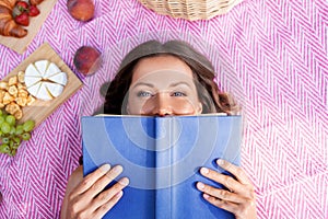 Happy woman reading book at picnic in summer park