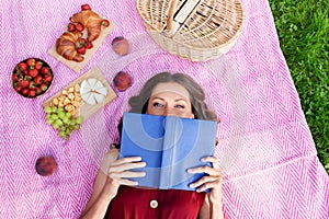 Happy woman reading book at picnic in summer park