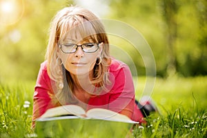 Happy woman reading a book during springtime in nature