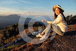 Woman reading a map siting on green grass meadow on top of mountain and enjoying nature ,sunrise in winter