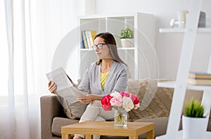 Happy woman reading newspaper at home