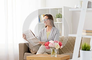 Happy woman reading newspaper at home