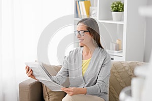 Happy woman reading newspaper at home