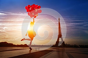 Happy woman with red balloons jumping near Eiffel tower in Paris